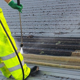 A member of staff waterblasting a roof